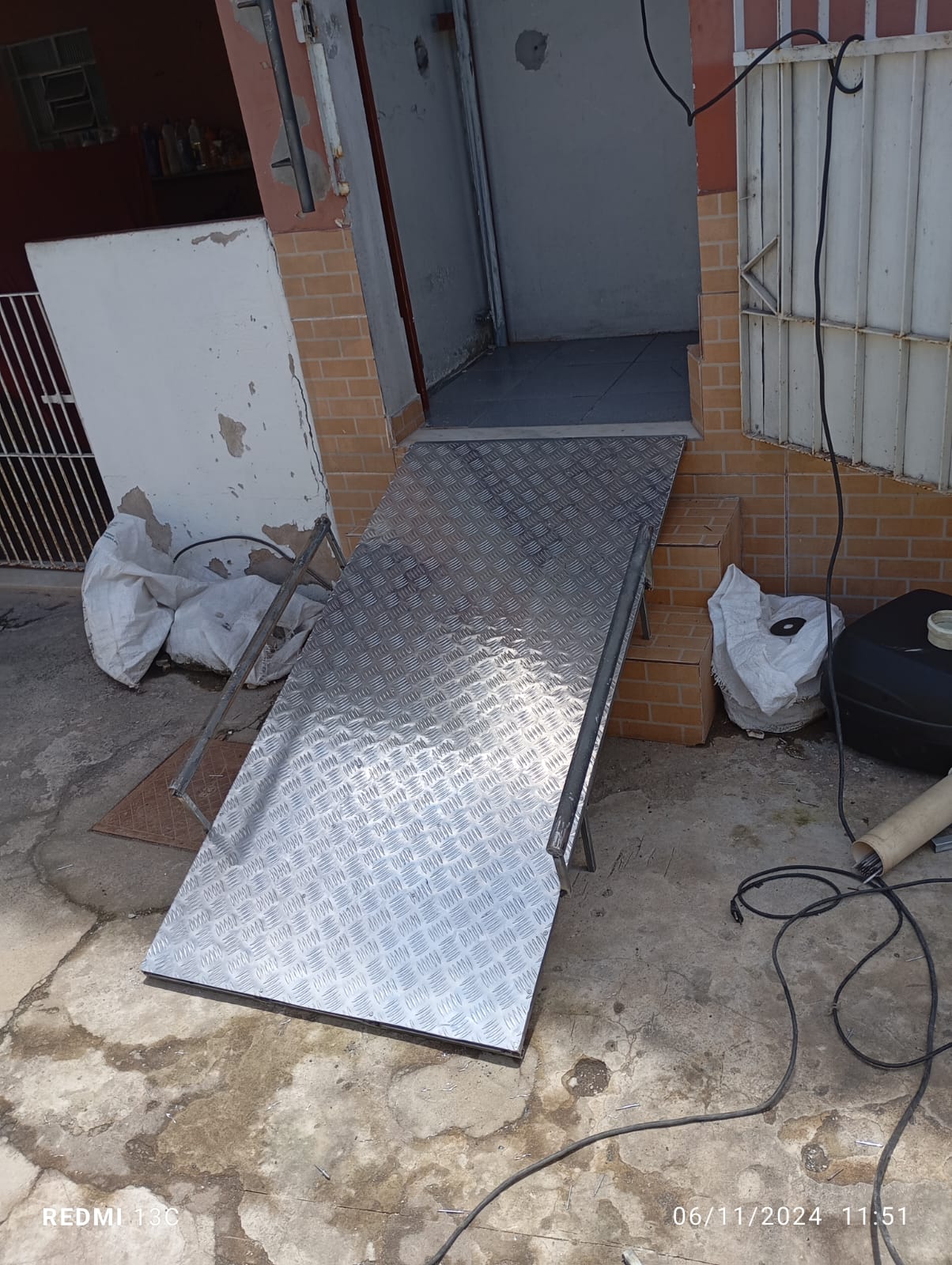 Rampa de acesso em chapa xadrez com corrimão soldado, vencendo os degraus da entrada